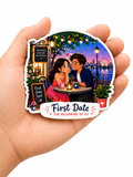 Fridge Magnet of a couple on a first date with a Ferris wheel in the background held in a hand.